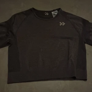 Lila träningströja från Lager157 - Säljer en lila croppad träningströja från Lager157 med rund hals och diskret logga på bröstet. Tröjan har lång ärm och är tillverkad i ett stretchigt syntetmaterial som passar perfekt till träning eller chill.