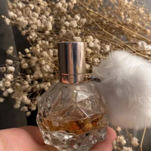 Ariana Grande parfym - Halvfull parfym från Ariana Grande i en kristallformad glasflaska med silvrigt lock och en stor vit fluffig boll som detalj. Doften är söt och flaskan är riktigt snygg att ha framme på hyllan.