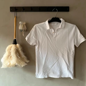 Vit piké t-shirt från Zara - Klassisk vit piké t-shirt från Zara med korta ärmar och krage. STRYKS INNAN POSTNING! T-shirten har knappar framtill och är gjord i mjuk bomull. Enkel och stilren modell som passar till det mesta. Perfekt för dig som gillar en clean och fräsch look.