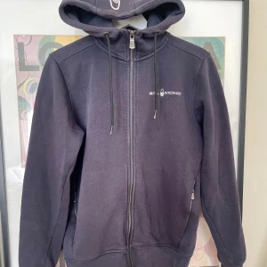 Sail Racing hoodie - Mörkblå hoodie från Sail Racing med hel dragkedja framtill, huva med snörning och två fickor med dragkedja. Kom privat för fler frågor och funderingar:)