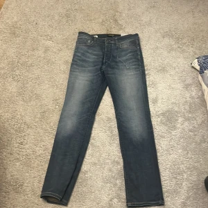 Slim straight jeans SlimStraight/Tim 28/30 - Mörkblå jeans med snygg tvätt och klassisk femficksdesign. Modellen är slim straight vilket ger en smal men rak passform. Jeansen har orangea sömmar och är tillverkade i ett mjukt denimtyg. Perfekta för dig som gillar stilrena och bekväma jeans. Har använt de ett fåtal gånger 
