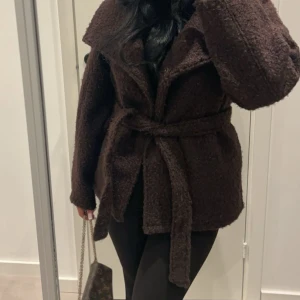 Mörkbrun teddykappa - Säljer denna supertrendiga kappa från Gina tricot, knappt använd och är som ny! Säljer pga för liten. Storlek xxs men passar om du är en xs💕