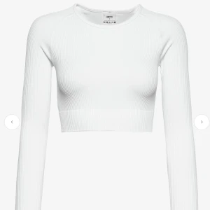 Vit ribbad croppad topp från AIMN - Säljer en vit croppad långärmad topp från AIMN. Toppen är ribbad och har en tight passform med rund halsringning. Tillverkad i stretchigt material som består av polyamid och elastan, perfekt för en sportig och trendig look. Pris 250kr, Ordinarie 549kr