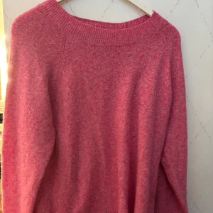 Rosa stickad tröja från Vero Moda - Mysig rosa stickad tröja från Vero Moda i storlek L. Tröjan har en rundad halsringning med ribbad kant och långa ärmar. Materialet är mjukt och fluffigt, perfekt för kyliga dagar. Enkel design som är lätt att matcha med jeans eller kjol. Har använda nån gång men är som ny. Perfekt nu till hösten 🍁🪾😍😍🛍️