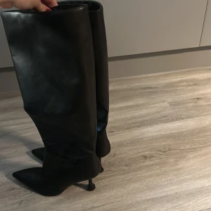 Svarta höga stövlar med klack - Säljer ett par svarta höga stövlar i skinn med spetsig tå och smal hög klack. Strl 41 men pga den spetsiga tån passar den mindre fötter också.