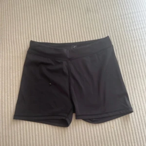 Svarta träningsshorts från Energetics - Svarta, tighta träningsshorts från Energetics. De har en enkel design med midwaist och är gjorda i ett stretchigt syntetmaterial som passar perfekt för träning eller sport. Snygga och bekväma shorts som är lätta att röra sig i.