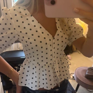 Prickig blus  - Så sött prickig blus! den är v ringad och är ingående i midjan och har lite puffiga ärmar. Så snygg och bra skick!