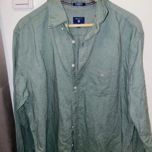 Grön oxfordskjorta från Gant XL - Snygg grön oxfordskjorta från Gant i regular fit. Skjortan har klassisk krage, bröstficka med broderad Gant-logga och knäppning framtill. Perfekt för dig som gillar en stilren och avslappnad look.