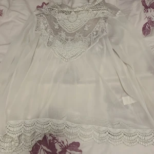Vit spetsblus  - Säljer en superfin vit blus, tyg och vackra spetsdetaljer både upptill och längs nederkanten. Blusen har lång ärm. (Den är genomskinlig blus) Hör av dig vid intresse!!!