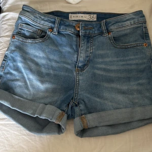 Blå jeansshorts från Amisu - Snygga blå jeansshorts från Amisu med klassisk femficksdesign och uppvikta benslut. Shortsen har normal passform, knapp och dragkedja framtill samt coola slitningar för en avslappnad vibe. Perfekta för varma dagar och chill häng.