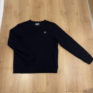 Mörkblå sweatshirt från Morris - En stilren mörkblå sweatshirt från Morris med rund hals och diskret broderad logga på bröstet. Tröjan har långa ärmar, ribbade muddar och är gjord i mjuk bomull. Perfekt för en chill och clean look. Denna är dunder fet och passar till allt, storlek S men det står att den är i M men den har krympt i storlek,  pris är diskuterbart! hör av dig vid minsta fundering!