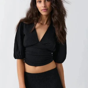 Svart topp - Svart croppad topp från Gina Tricot med djup v-ringning och puffiga halvlånga ärmar. 