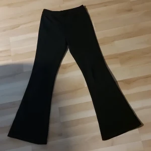 Svarta bootcut byxor från Kappahl - Svarta bootcut byxor från Kappahl i storlek 164. Byxorna har en klassisk utsvängd passform och är tillverkade i ett mjukt och stretchigt material som sitter skönt på kroppen. Perfekta för dig som gillar en stilren och trendig look och samtidigt vill hålla dig varm.