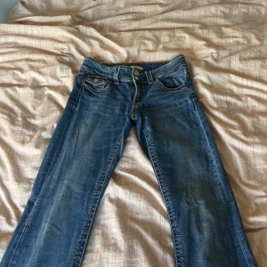 Blå jeans från Gina Tricot, storlek 164 - Säljer ett par klassiska blå jeans från Gina Tricot i storlek 164. Jeansen har fyra fickor, normal passform och lite utsvängda ben. Snygg tvätt med lätt slitning och kontrastsömmar. Perfekta till sneakers eller boots.