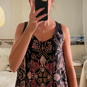 Mönstrad linnetopp från Odd Molly - Supersnygg linnetopp från Odd Molly med unikt mönster i svart, rosa och gult. Toppen är ärmlös med v-ringning och har en flowy passform. Tillverkad i mjuk viskos som känns lätt och skön mot huden. Perfekt för dig som gillar boho-vibes och coola detaljer.