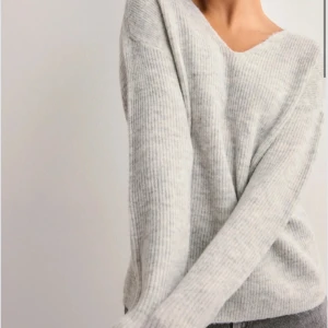 Ljusgrå ribbstickad tröja med v-ringning - Supermjuk ljusgrå ribbstickad tröja med v-ringad hals och långa ärmar. Perfekt oversized fit för en chill och avslappnad look. Passar grymt till både jeans och kjol. Enkel att styla och sjukt skön att ha på sig hela dagen. Helt ny med prislapp