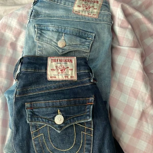 True Religion bootcut & flare jeans - Två par True Religion jeans: ett par mörkblå Becca mid rise bootcut och ett par ljusblå Joey low rise flare. Båda har ikoniska bakfickor med kontrastsömmar och silverfärgade knappar. Klassisk jeanslook med snygga detaljer och grym passform. båda säljs för ett pris