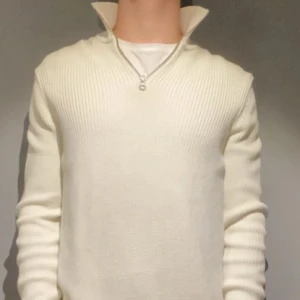 Vit stickad tröja med half zip - Säljer en stilren vit stickad tröja med ribbad struktur och half zip-dragkedja vid halsen. Tröjan har lång ärm och hög krage som kan bäras uppvikt för extra edge. Perfekt för dig som gillar en clean och enkel look.