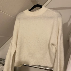 Vit stickad tröja från NA-KD - Säljer en vit stickad tröja från NA-KD. Tröjan har en kort modell med långa ärmar och en rund halsringning. Den har noppor 🩷