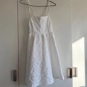 Vit klänning från Bubbleroom - Säljer en elegant vit klänning från Bubbleroom med smala axelband och ett vackert texturerat mönster. Klänningen har en fin passform och är perfekt för speciella tillfällen. Perfekt för sommarens fester! 🌸
