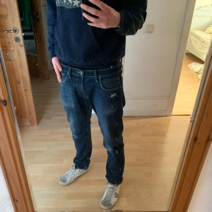 Mörkblå jeans från Lee - Säljer ett par mörkblå jeans från Lee med slitna detaljer. De har en klassisk femficksdesign och en knappgylf. Perfekta för en avslappnad stil.