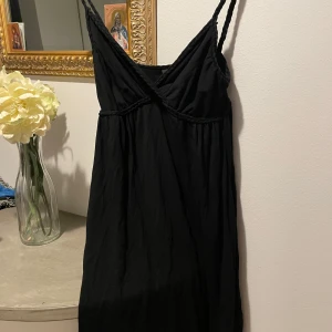 Svart klänning från H&M - Snygg svart klänning från H&M med smala axelband och v-ringad design. Perfekt för en stilren look. Klänningen har en enkel och elegant stil som passar till många tillfällen.