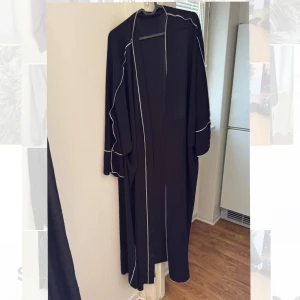 Abaya med sjal - Elegant svart lång abaya med vita kantdetaljer och en matchande sjal.