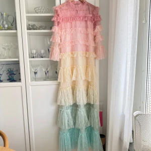 By Malina Carmine maxiklänning - Säljer en fantastisk långklänning från By Malina i storlek M. Klänningen har ett vackert lager-på-lager mönster i rosa, gult och grönt med volanger och spetsdetaljer. Regnbågsfärgad i denna modell säljs ej längre på deras hemsida. Går att kolla modellen annars på hemsidan. Den har 3/4 ärmar och en dragkedja i ryggen. Perfekt för speciella tillfällen! Köpt för att ha till bal/bröllop men alldeles för lång, så aldrig använd. Ny med prislapp! Storlek M