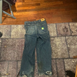 Blå jeansbyxor med verktygsfickor - Säljer ett par blå jeansbyxor med praktiska verktygsfickor och en klassisk femficksdesign. Byxorna har en avslappnad passform och är perfekta för arbete eller fritid. De har en robust känsla och är gjorda för att hålla länge.