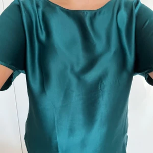 Grön satinblus - Snygg grön blus i satin med korta ärmar och rund halsringning. Perfekt för en stilren look. Den är från intimissmi i storlek S men skulle säga den passar M också💞använd ett fåtal gånger!