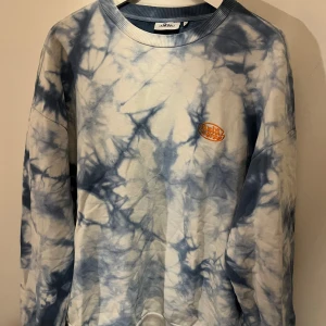 Blå och vit batikmönstrad tröja från junkyard (multiverse) - Säljer en cool blå och vit batikmönstrad tröja från junkyard. Tröjan har långa ärmar och en rund halsringning. Perfekt för en avslappnad stil med en unik touch. 🌀