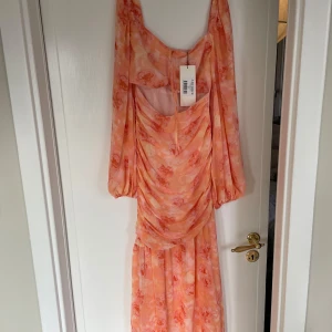 Peach Porto Maxi Dress från ADOORE - Sååå  vacker peachfärgad Porto Maxi Dress från ADOORE. Klänningen har ett blommigt mönster och långa ärmar. Den är perfekt för sommaren! Bara för liten för mig - helt oanvänd! 