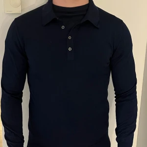 Marinblå pikétröja från Oscar Jacobson - Säljer en stilren marinblå pikétröja från Oscar Jacobson. Skicket på tröjan är näst in till helt nytt 10/10. Extremt skön tröja gjord av 100% merino ull. Storlek s på tröjan, men passar även M. Ingår även en extra knapp till tröjan ifall nån av dem går sönder. Vid intresse eller frågor skriv dm.