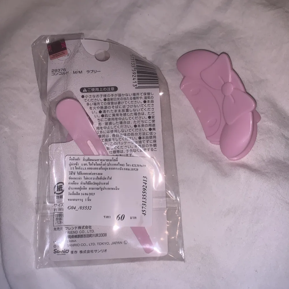 Söt rosa hårklämma med en stor rosett. Perfekt för att ge en gullig touch till din frisyr. Kommer i en förpackning med prickigt mönster och en illustration av en karaktär med rosett. Karaktären heter My melody. Asusteet.