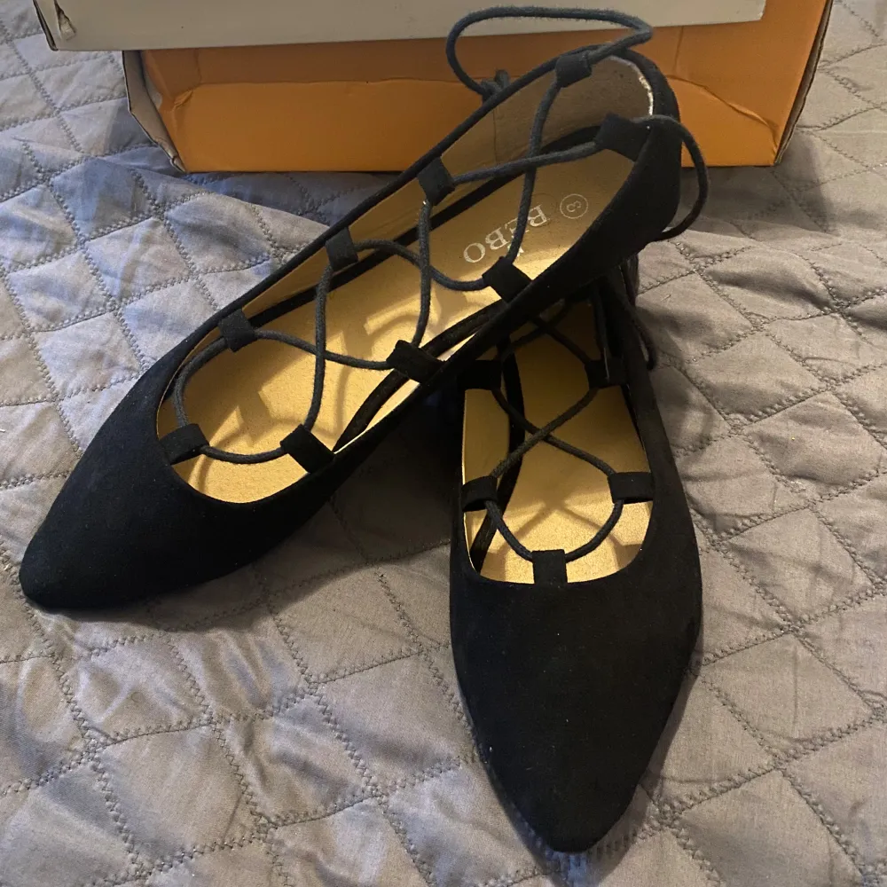 Snygga svarta ballerinaskor från Bebo med spetsig tå och elegant snörning. Perfekta för en stilren look.. Kengät.
