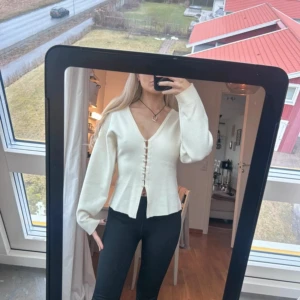 Gina knitted sculptured cardigan  - Säljer en stilren vit kofta med knappar framtill. Koftan har en v-ringad design och långa ärmar, perfekt för en elegant look. Passar bra till både jeans och kjol.