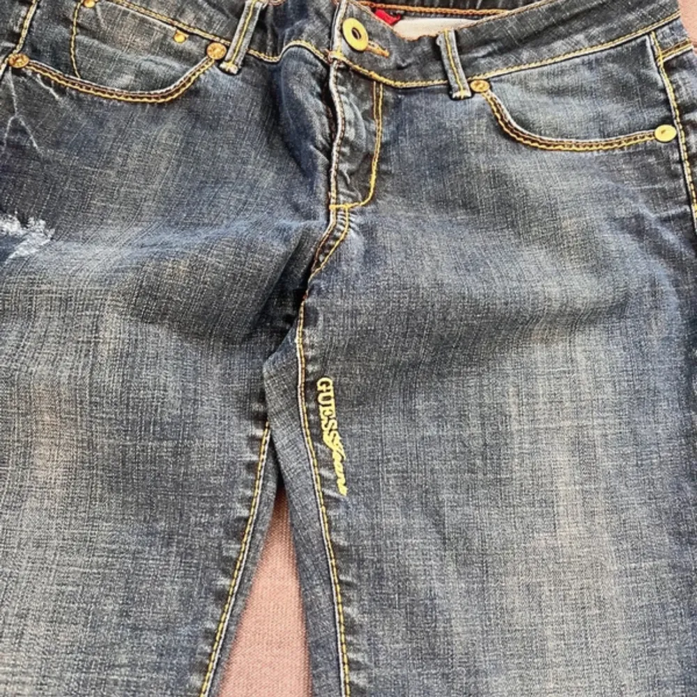 Säljer ett par klassiska blå jeans från Guess. De har en straight passform med snygga slitningar och kontrastsömmar. Perfekta för en avslappnad stil. Storlek 32. 40cm tvärsöver. Pris går att diskuteras!🩷. Farkut & Housut.