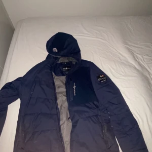 Mörkblå jacka från Sail racing - Säljer en mörkblå jacka från sail racing med huva och dragkedja. Jackan har en broderad logga på ärmen och en liten logga på luvan. Pris går att diskutera