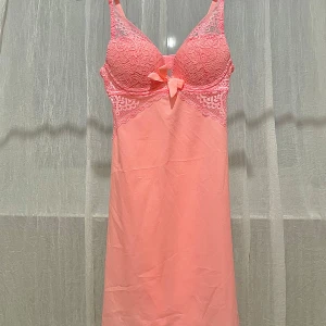 Nattlinne från Censored i aprikos färg - Säljer ett sött rosa nattlinne från Censored med spetsdetaljer och en rosett framtill. Nattlinnet har justerbara axelband. STORLEK 34 och passar byst 80-85cm.