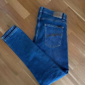 Blå jeans från Nudie Jeans - Säljer ett par snygga blå jeans från Nudie Jeans. De har en klassisk femficksdesign och en normal passform. Perfekta för en avslappnad stil.