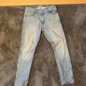 Ljusa jeans från Wrangler - Snygga ljusblå jeans från Wrangler i modellen Larston. De har en slim tapered passform och är tillverkade i klassiskt denimtyg. Perfekta för en stilren look. 