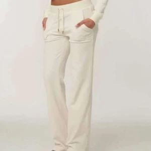 Vita mjukisbyxor juicy couture  - Snygga vita mjukisbyxor med hög midja och snörning i midjan. Byxorna har en loose passform och är perfekta för en avslappnad stil. De har praktiska fickor och en diskret logga på sidan.