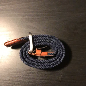 Blått flätat bälte Jack&Jones - Snyggt blått flätat bälte med bruna läderdetaljer och en stilren metallspänne. Perfekt för att ge en avslappnad men ändå stilfull touch till din outfit. 600kr nypris helt clean