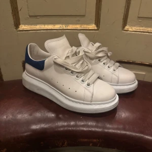 Alexander McQueen vita sneakers blå detalj - Chunky vita sneakers från Alexander McQueen med blå mockadetalj på hälen. Dom är i superbra skick. Säljer då de är för små. Öppen för bud 
