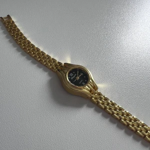 Guldfärgad klocka  - Snygg guldfärgad klocka från Chaoyada med svart urtavla och tydliga siffror. Länken är i metall med klassisk design och är i rostfritt stål. Quartz-urverk och elegant rund form, perfekt för dig som gillar lite mindre och feminina klockor. Länken är 15 cm men det medföljer en extra länk. Boetten är 20 mm. Köpt på en marknad här i Sverige men importerad från Italien 