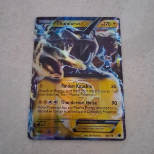 Thundurus EX - Cool Pokémon-kort med Thundurus EX! Perfekt för dig som samlar eller spelar Pokémon TCG. Kortet har kraftfulla attacker som Raiden Knuckle och Thunderous Noise. Snyggt motiv och passar både nybörjare och erfarna spelare. Ett måste för alla Pokémon-fans!
