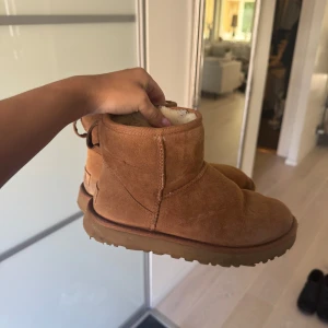 Bruna UGG boots i mocka - Mysiga bruna UGG boots i klassisk modell med rund tå och platt sula. Utsidan är i mjuk mocka och insidan är fodrad med fluffigt material som håller fötterna varma. Perfekta för kyliga dagar och en chill look. Pris kan diskuteras. 