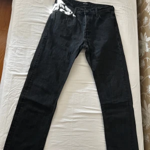 Svarta relaxed jeans Jack & Jones - Svarta jeans från Jack & Jones i modellen Relaxed Chris. De har en avslappnad passform med raka ben och klassisk femficksdesign. Jeansen är tillverkade i bomull och har en mörk tvätt som ger en stilren look. Jeansen är i storlek 31 32