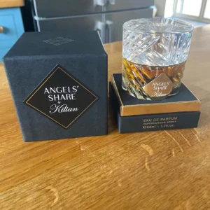 Angels' Share by Kilian parfym - Exklusiv parfym från Kilian, Angels' Share, i en lyxig kristallin glasflaska med guldiga detaljer. Flaskan rymmer 100ml Eau de Parfum och kommer i en elegant svart ask med guldkant. Doften är känd för sina varma, rika och sofistikerade toner.