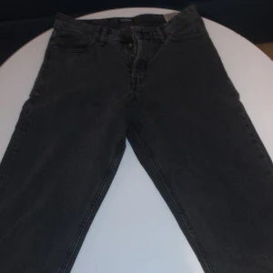 Svarta loose fit jeans Jack & Jones - Svarta jeans från Jack & Jones i modellen Loose/Eddie. De har en loose fit med raka ben och klassisk femficksdesign. Jeansen är tillverkade i denim och har en mörk tvätt som ger en cool och avslappnad vibe.